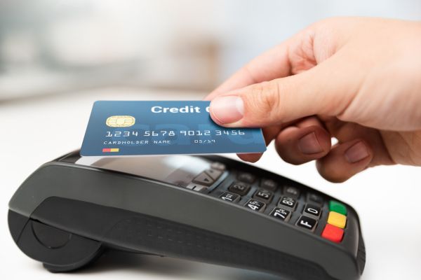 Hand holding a credit card above a POS terminal